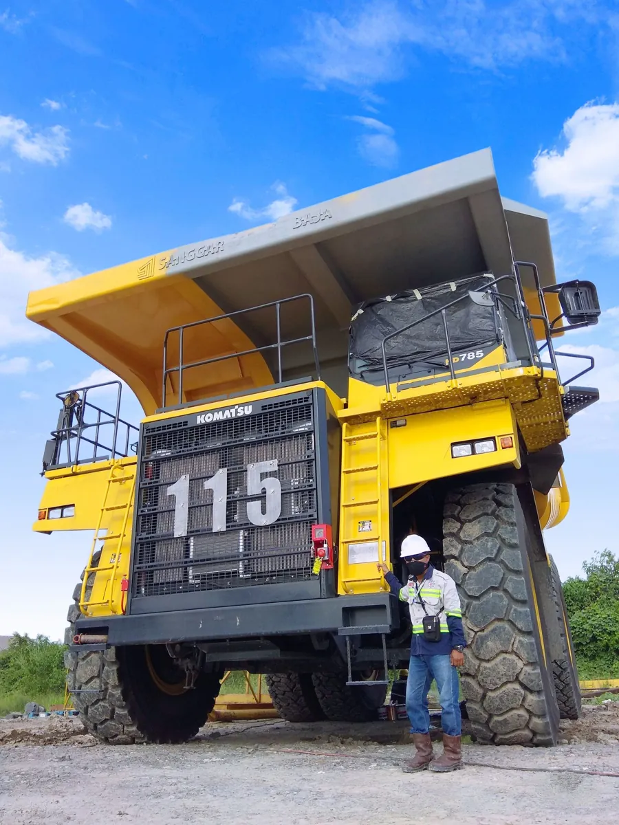 Worker standing beside a large Komatsu mining truck